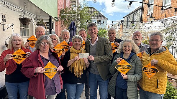 A group of Bridport & Chesil Bank Liberal Democrat Candidates and Councillors stood with Edward Morello stood outside the Bull Hotel holding 'Liberal Democrats Winning Here' window posters.