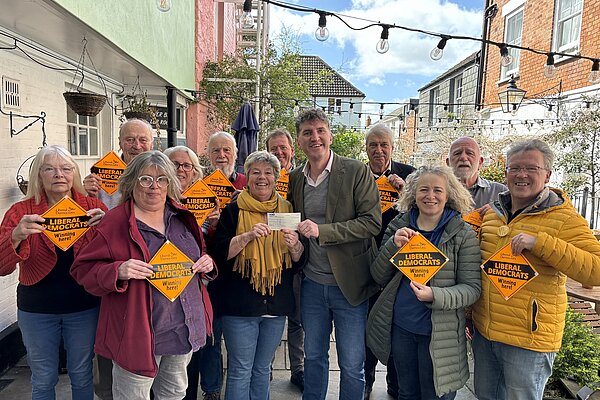 A group of Bridport & Chesil Bank Liberal Democrat Candidates and Councillors stood with Edward Morello stood outside the Bull Hotel holding 'Liberal Democrats Winning Here' window posters.