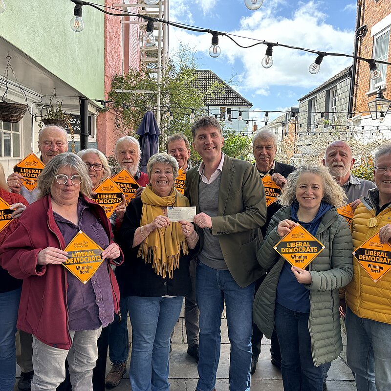 A group of Bridport & Chesil Bank Liberal Democrat Candidates and Councillors stood with Edward Morello stood outside the Bull Hotel holding 'Liberal Democrats Winning Here' window posters.