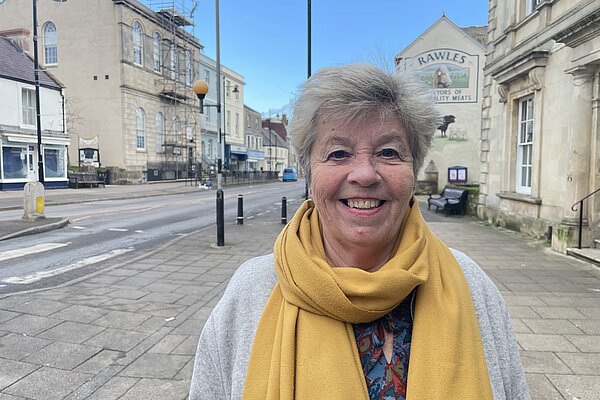 Bridget Bolwell in yellow scarf standing in Bridport.