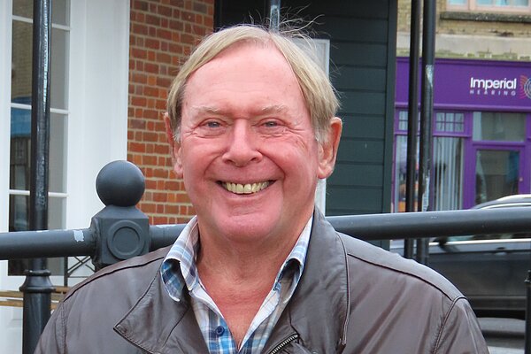 David Leaper wearing a brown leather jacket and smiling