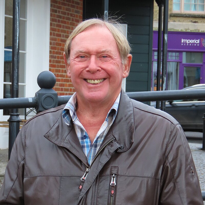 David Leaper wearing a brown leather jacket and smiling