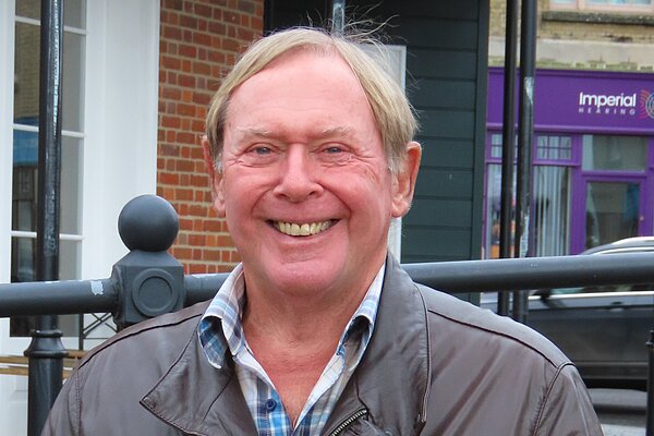 David Leaper wearing a brown leather jacket and smiling