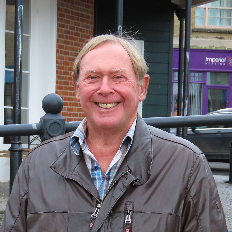 David Leaper wearing a brown leather jacket and smiling