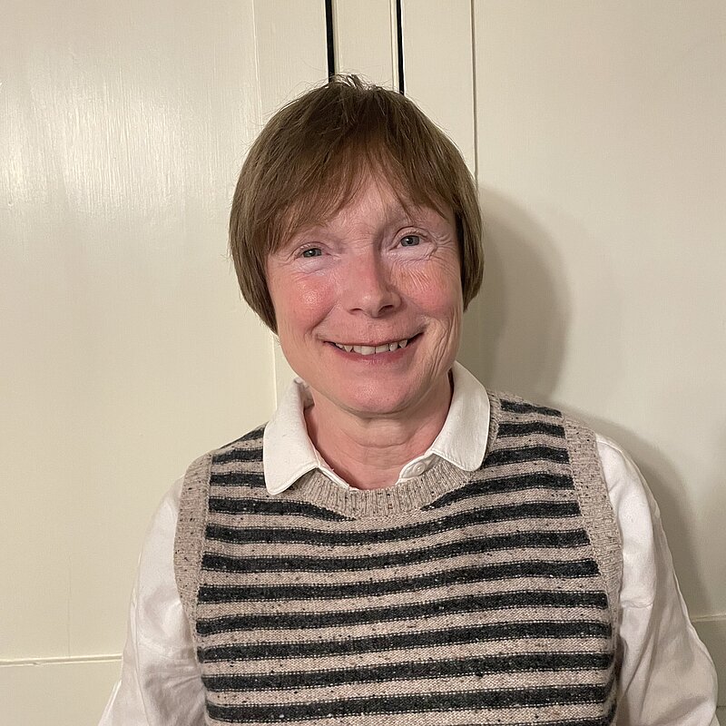 Ann Langridge wearing a white shirt and a blue and grey striped, knitted vest.