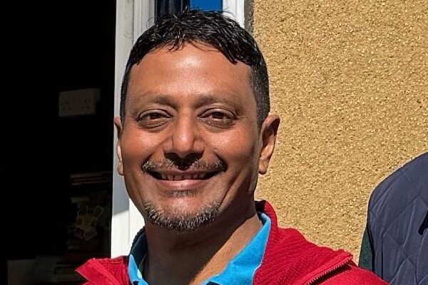 Suresh wearing a red jacket and blue polo shirt