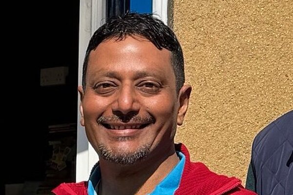 Suresh wearing a red jacket and blue polo shirt