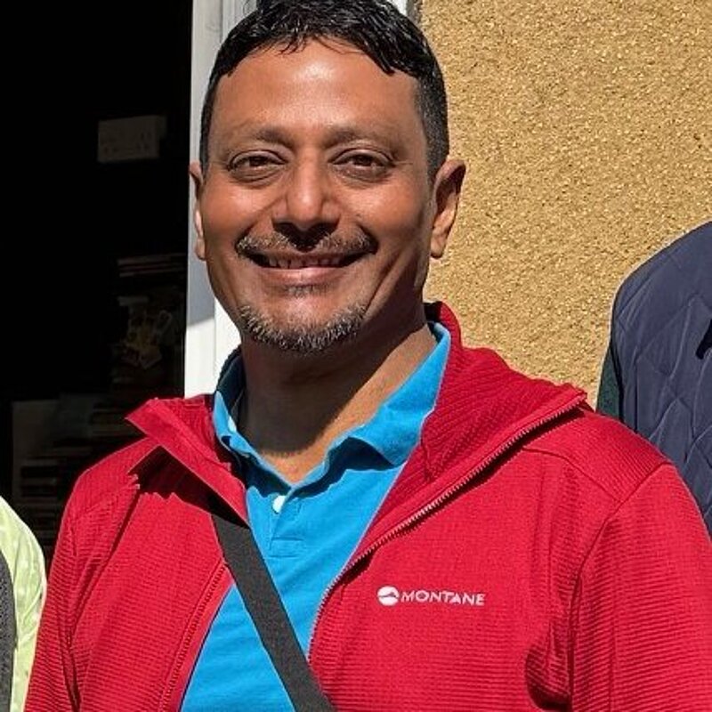 Suresh wearing a red jacket and blue polo shirt