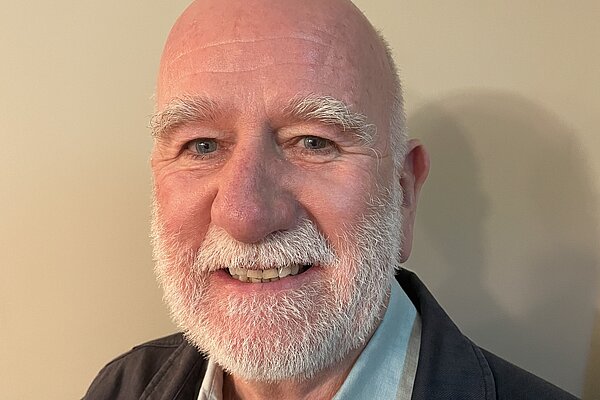Ian Bark with a white beard, wearing a blue shirt