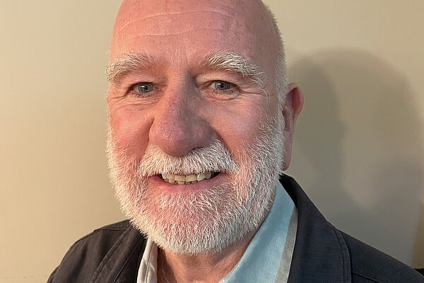 Ian Bark with a white beard, wearing a blue shirt
