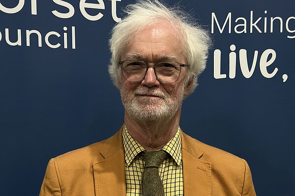 Dorset Councillor for Sherborne Rural ward and Sherborne Town Council Councillor, Robin Legg stood in front of a Dorset Council graphic at the Dorset Council Count on the 3rd May 2024
