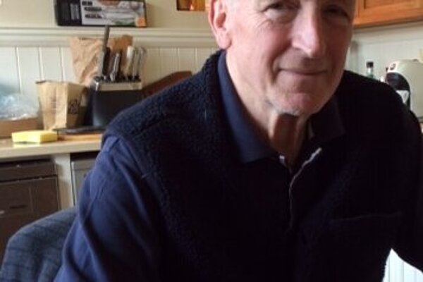 Guy Patterson wearing a navy polo shirt in his kitchen at his kitchen table