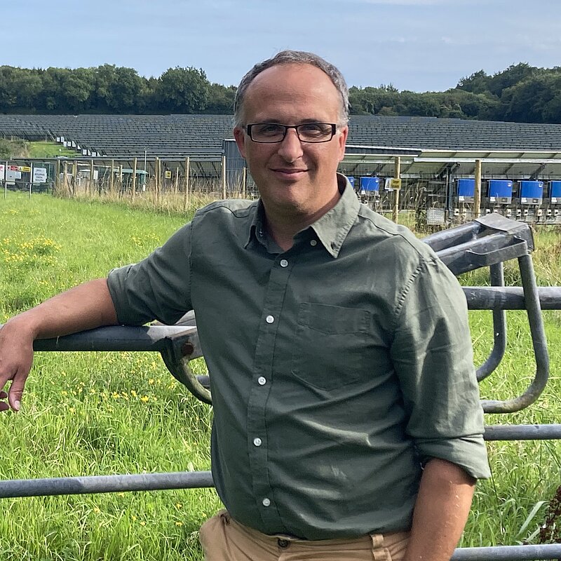 Neil Eysneck in a green shirt standing next to a gate.