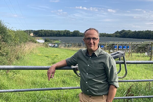 Neil Eysneck in a green shirt standing next to a gate.