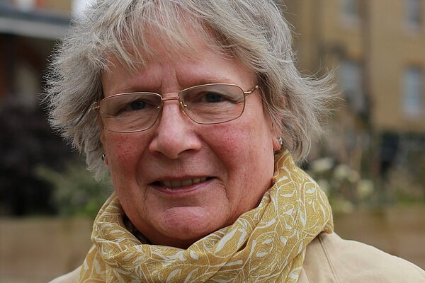 Frances Hogwood in 2019, wearing a beige trench coat and yellow scarf