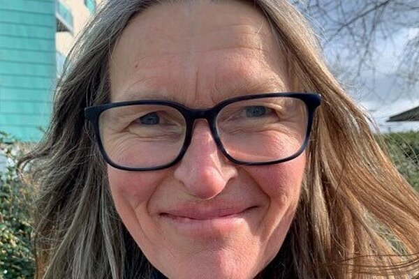 Kate Reid in black framed glasses and a blue scarf