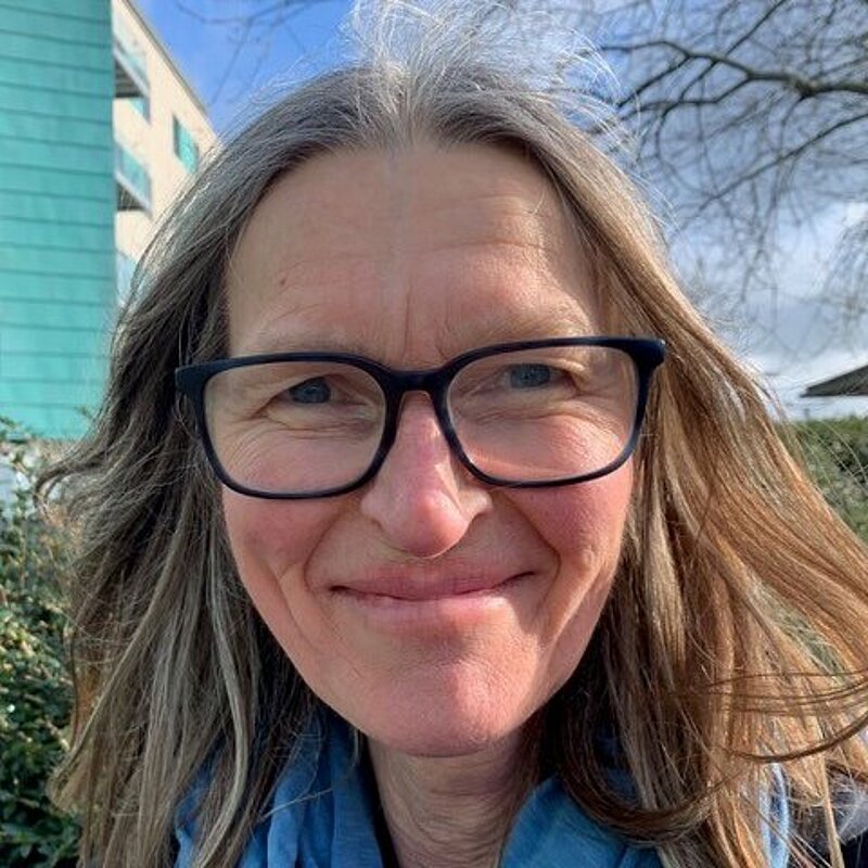 Kate Reid in black framed glasses and a blue scarf
