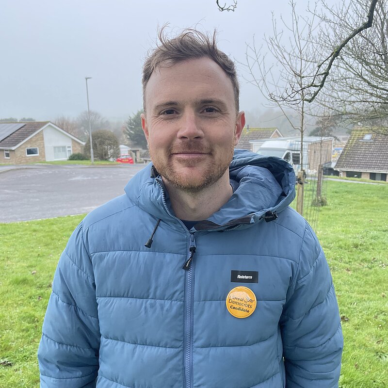 Andy Holdridge wearing a blue puffer jacket and a Liberal Democrat pin badge