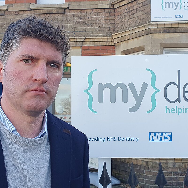 Edward Morello with an angry expression outside of a 'My Dentsit' office