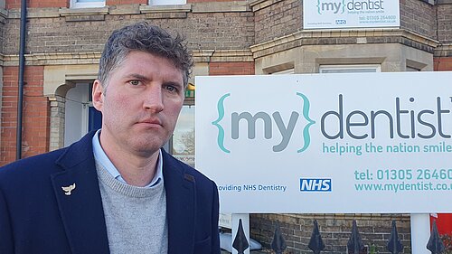 Edward Morello with an angry expression outside of a 'My Dentsit' office