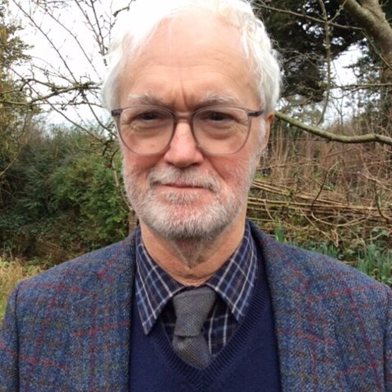 Robin Legg with glasses and sweater standing in front of tree.