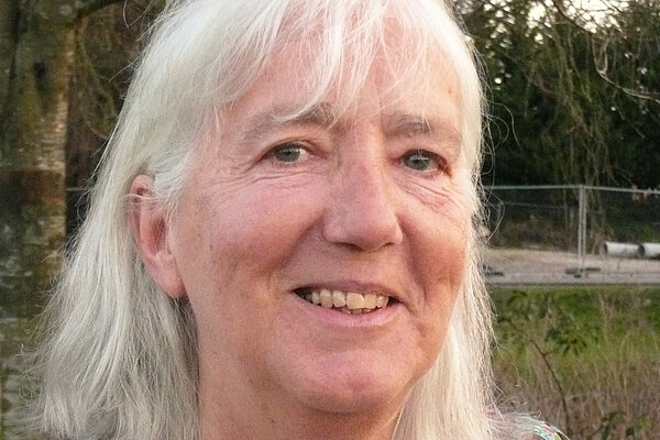 Stella Jones has long grey hair and is wering a pink multicolour blouse