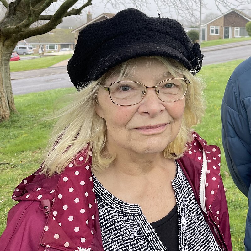 Anne Rickard, wearing a black beret, black and white top, and pink jacket. She is stood with Andy Holdridge, wearing a Blue puffer jacket.