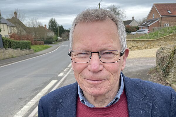 Chris Kippax wearing ared jumper and navy blue suit jacket in Longburton