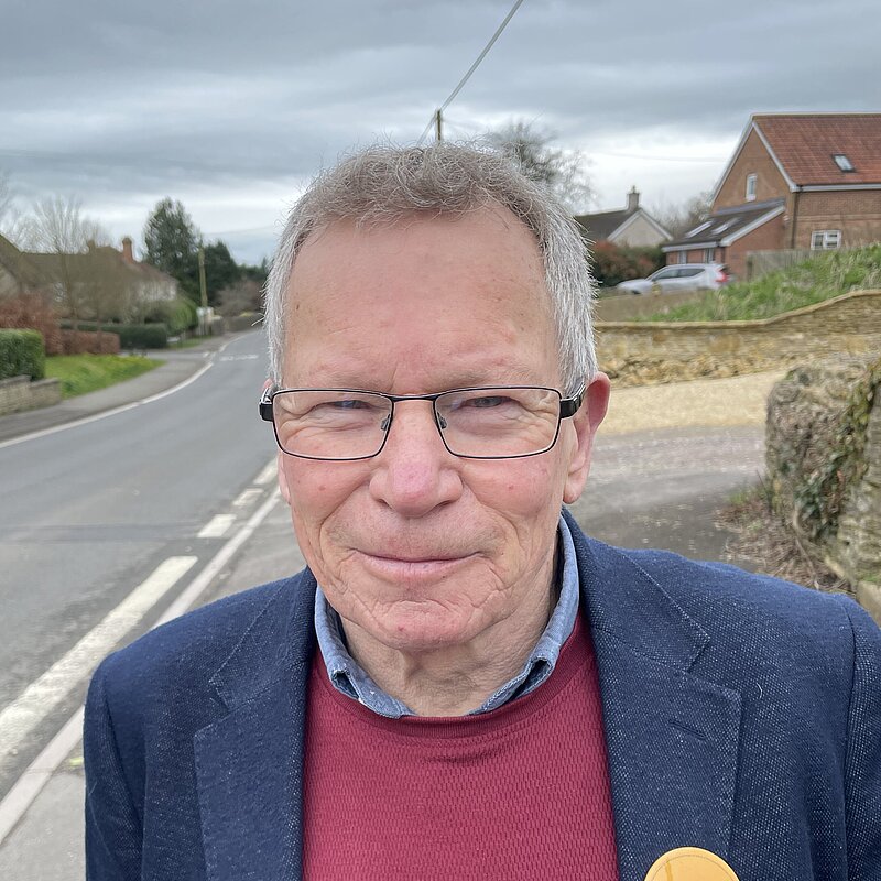 Chris Kippax wearing ared jumper and navy blue suit jacket in Longburton