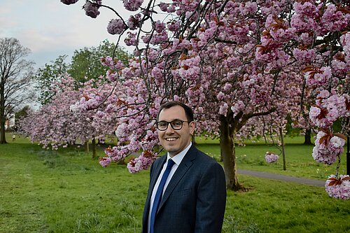 Tom Gordon stood on the Stray in front of blossoming trees