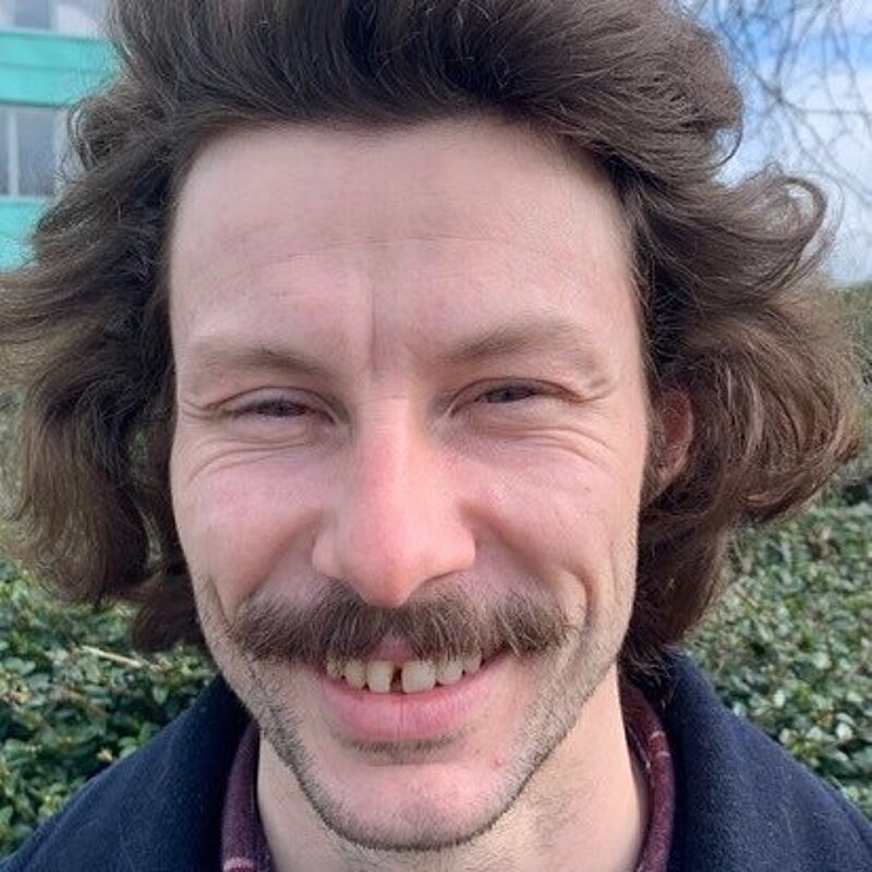 Rory Major with a moustache and wearing a red checked shirt and blue jacket